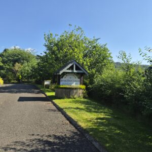 Welcome to River Edge Lodges sign on the wishing well with Moncreiffe Hill in the background