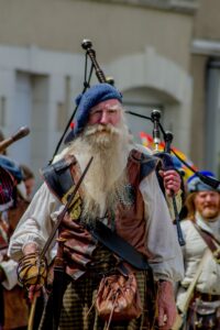Bearded man in tradtional Scottish dress carrying bagpipes